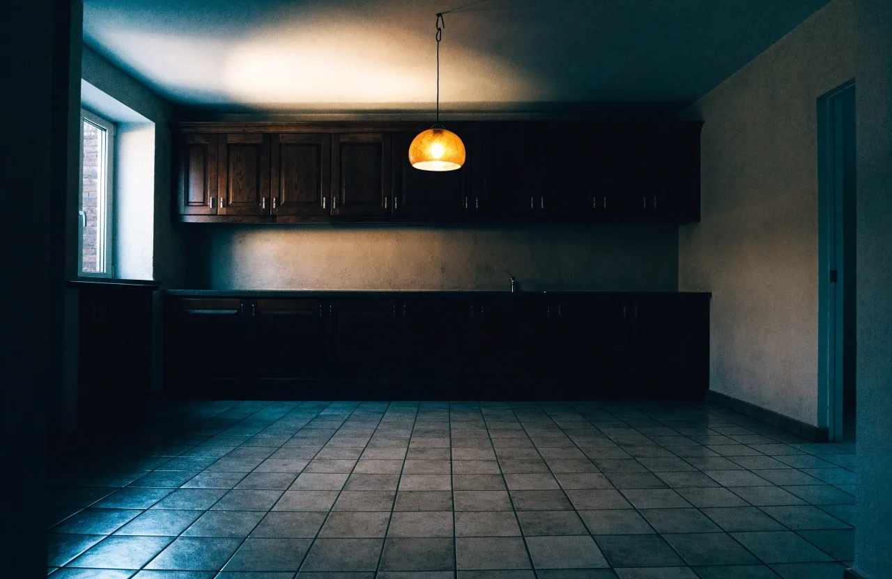 Cocina vacía de un piso en alquiler iluminada por una lámpara ámbar
